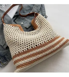Detail of woven straw shoulder bag with beige brown stripes and leather strap