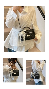 Detail view of black quilted crossbody bag with pearl lace bow and metal chain strap
