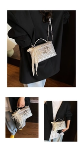 Close-up of quilted silver crossbody bag featuring pearl lace bow and chain strap details