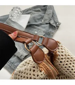 Detailed close-up of woven tote bag featuring leather straps and golden hardware rings
