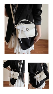 Détail d'un sac enveloppe blanc vintage avec nœud en dentelle et pendentif perle