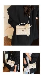 Detail of white quilted crossbody bag with pearl lace scarf and silver metal twist lock