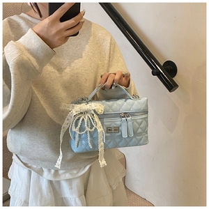 Detail of light blue quilted vanity bag with pearl charms and lace bow decoration