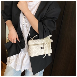 Close-up of white quilted mini box bag with silver twist lock and pearl tassel detail