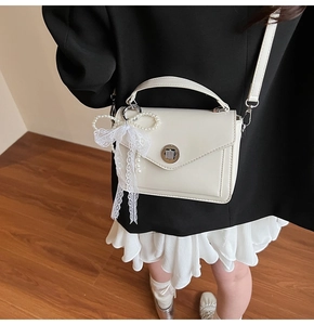 Détail du petit sac à main en cuir beige avec fermoir en métal et nœud perlé