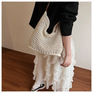 Detail of crochet mesh tote bag with large open weave and brown leather strap accents