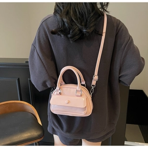 Detail showing pink glossy patent leather pillow bag with shoulder strap worn by a model