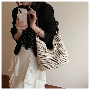 Detail of hollow-out cream straw bag featuring a brown leather strap and woven texture