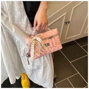Detailed shot of pink quilted handbag featuring lace bow and pearl chain handle details