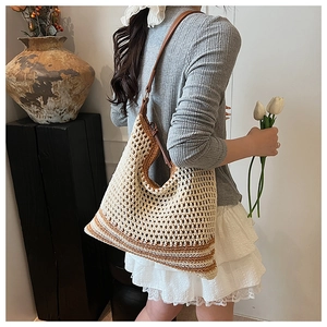 Detailed close-up of handmade hollow crochet straw tote bag with brown leather strap