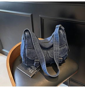 Detailed view of dark blue denim shoulder bag with metal buckles on vintage chair