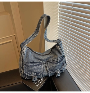 Detailed close-up of blue wash denim texture and utility pockets on retro hobo shoulder bag