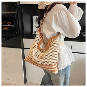 Detail of handwoven hollow mesh texture on straw tote bag with brown leather strap