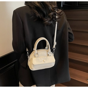 Close-up of a cream-colored patent leather mini handbag with a high-gloss finish and strap