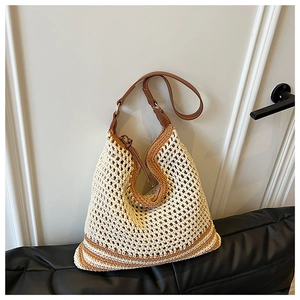 Detailed texture of handwoven crochet straw tote with brown faux leather strap and zip detail