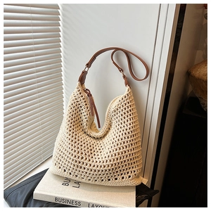 Detail of hollow woven straw underarm bag with brown leather strap and French minimalist style