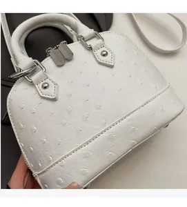 Dettaglio ravvicinato della borsa bianca con trama in pelle di struzzo e cerniera argento