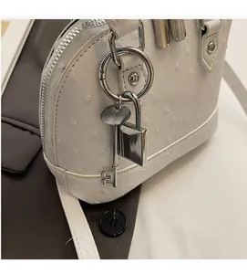 Dettaglio borsa bianca in pelle goffrata struzzo con lucchetto e chiavi argento