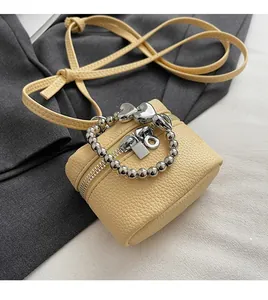 Detail view of mini yellow box bag with pebble leather texture and silver bead chain