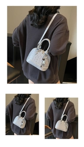 Dettaglio mini borsa a conchiglia azzurra con trama struzzo e ciondolo in argento