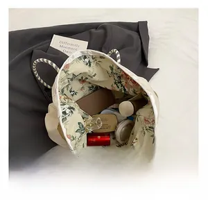 Vue de dessus du grand sac cabas en toile montrant l'intérieur fleuri et des cosmétiques