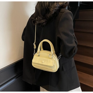 Rear view of a model wearing a pale yellow mini pillow bag with a black blazer