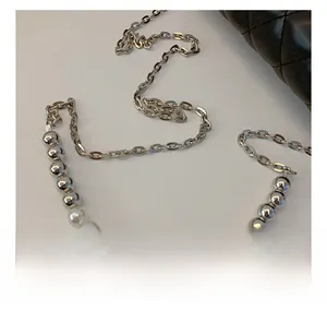 Détail de la bandoulière de luxe avec perles argentées, perles nacrées et chaîne