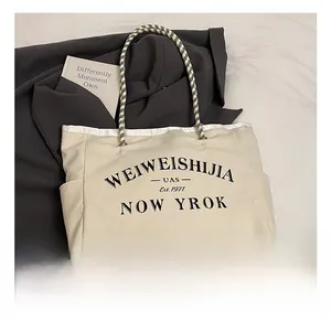Gros plan d'un sac cabas en toile crème avec poignées tissées et détails imprimés