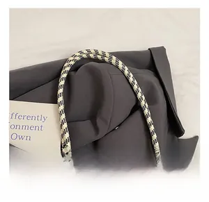 Gros plan sur la poignée tissée à carreaux noir et blanc et le sac fourre-tout gris