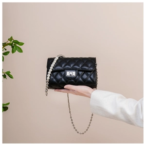 Détail du mini sac à rabat matelassé noir avec chaîne en perles et fermoir rotatif argenté