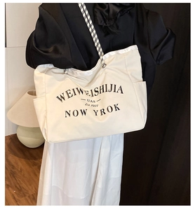 Détail du sac cabas en toile blanche avec lettres noires et bandoulière en corde tressée