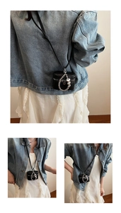 Close-up of black litchi grain mini crossbody bag with silver heart chain and zipper