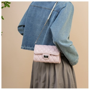 Détail du sac bandoulière matelassé rose avec chaîne en perles et fermoir rotatif