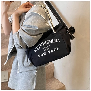 Détail du sac cabas en toile noire avec lettrage rétro et bandoulière en corde à carreaux
