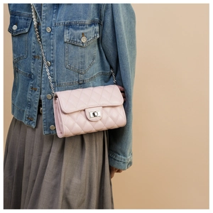 Détail d'un sac à rabat matelassé rose avec fermoir argenté et bandoulière chaîne