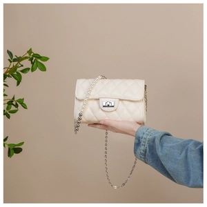 Détail d'un sac à bandoulière matelassé crème avec lanière en perles et chaîne