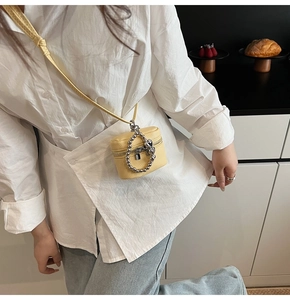 Detail of yellow lychee leather mini crossbody bag with silver bead chain and heart charm