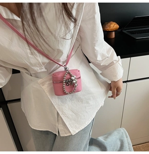 Detailed close-up of pink pebbled leather mini crossbody bag with heart bead chain