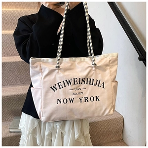 Détail d'un sac fourre-tout en toile rose clair avec anses en corde et imprimé lettres