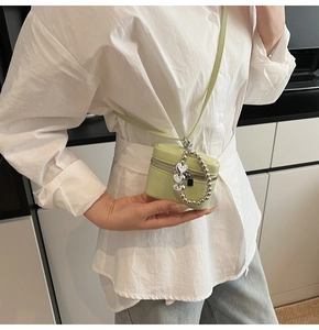 Detailed view of mini mint green lychee leather crossbody bag with heart charm chain