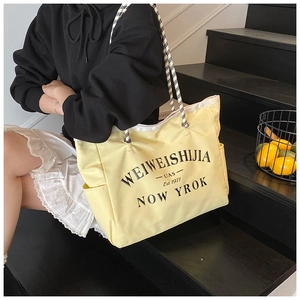 Détail du sac fourre-tout en toile avec anses tressées et lettrage noir imprimé
