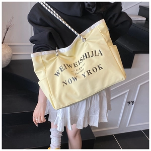 Détail du sac cabas jaune vif avec imprimé lettres et poignée tissée à carreaux