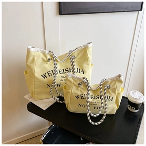 Détail du sac cabas en toile jaune avec anses à damier et lettrage imprimé New York