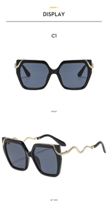 Detail of square black sunglasses featuring textured gold wave temples and dark lenses