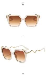 Detail view of square beige sunglasses featuring luxurious gold snake temples and brown lenses