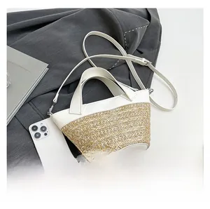 Detail view of woven straw bucket bag with white leather contrast and silver hardware