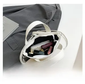 Practical internal capacity of the woven bucket bag showing phone and cosmetics