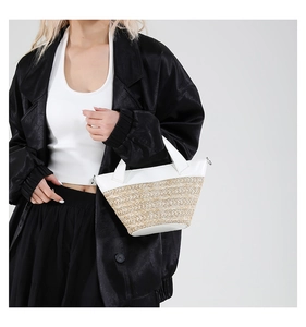 Detailed view of woven straw bucket bag with white leather trim styled on a model