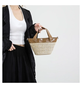Detail of woven straw handbag featuring brown leather trim and metal D-rings for straps