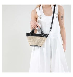 Detail of woven straw bucket bag with black leather trim and silver hardware on a model